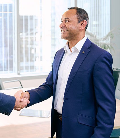 Hanif Ibrahim shaking hands with a client in an office setting, representing a partnership at The Finance Agency