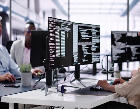 Two colleagues working at computers in an office, focusing on asset finance opportunities and financial planning tasks